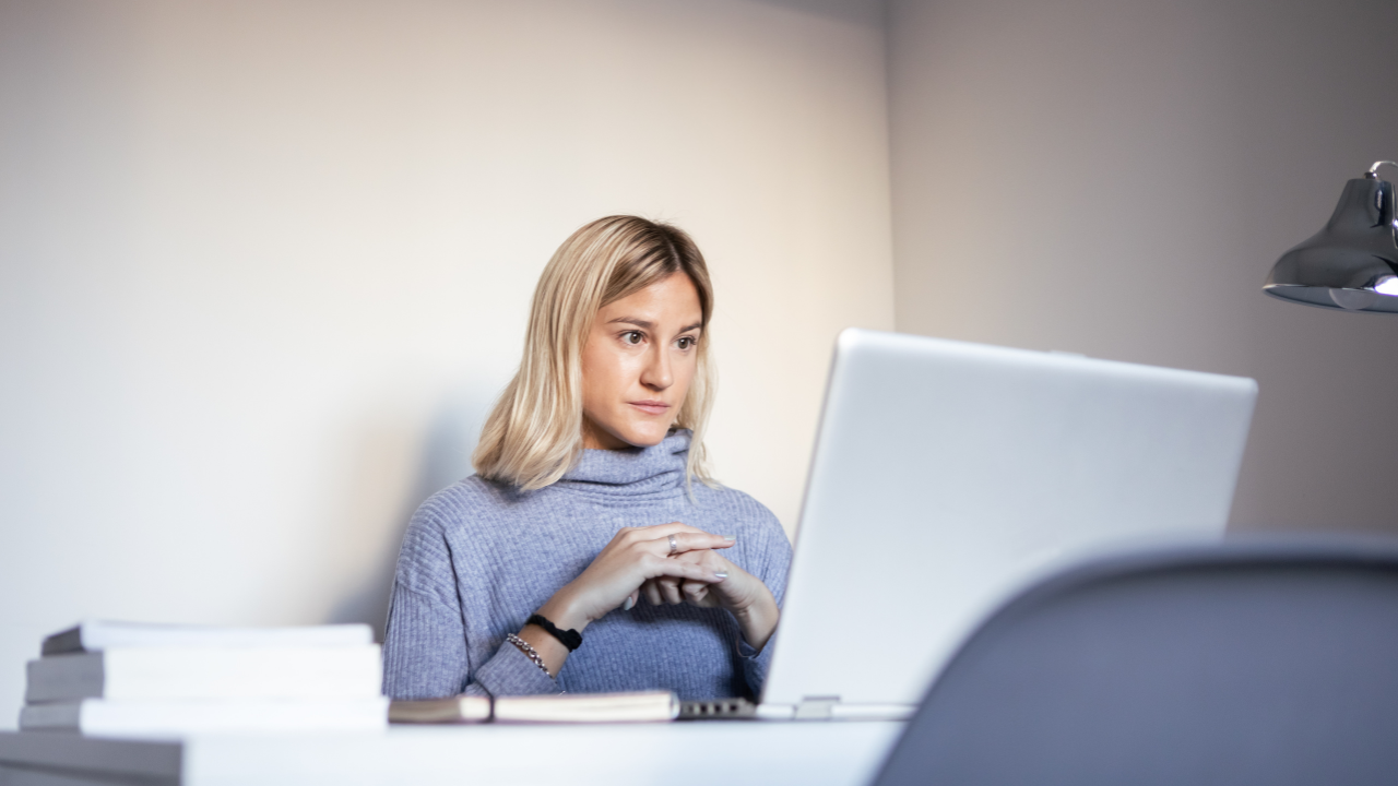 A woman on her computer with a stressed look on her face.